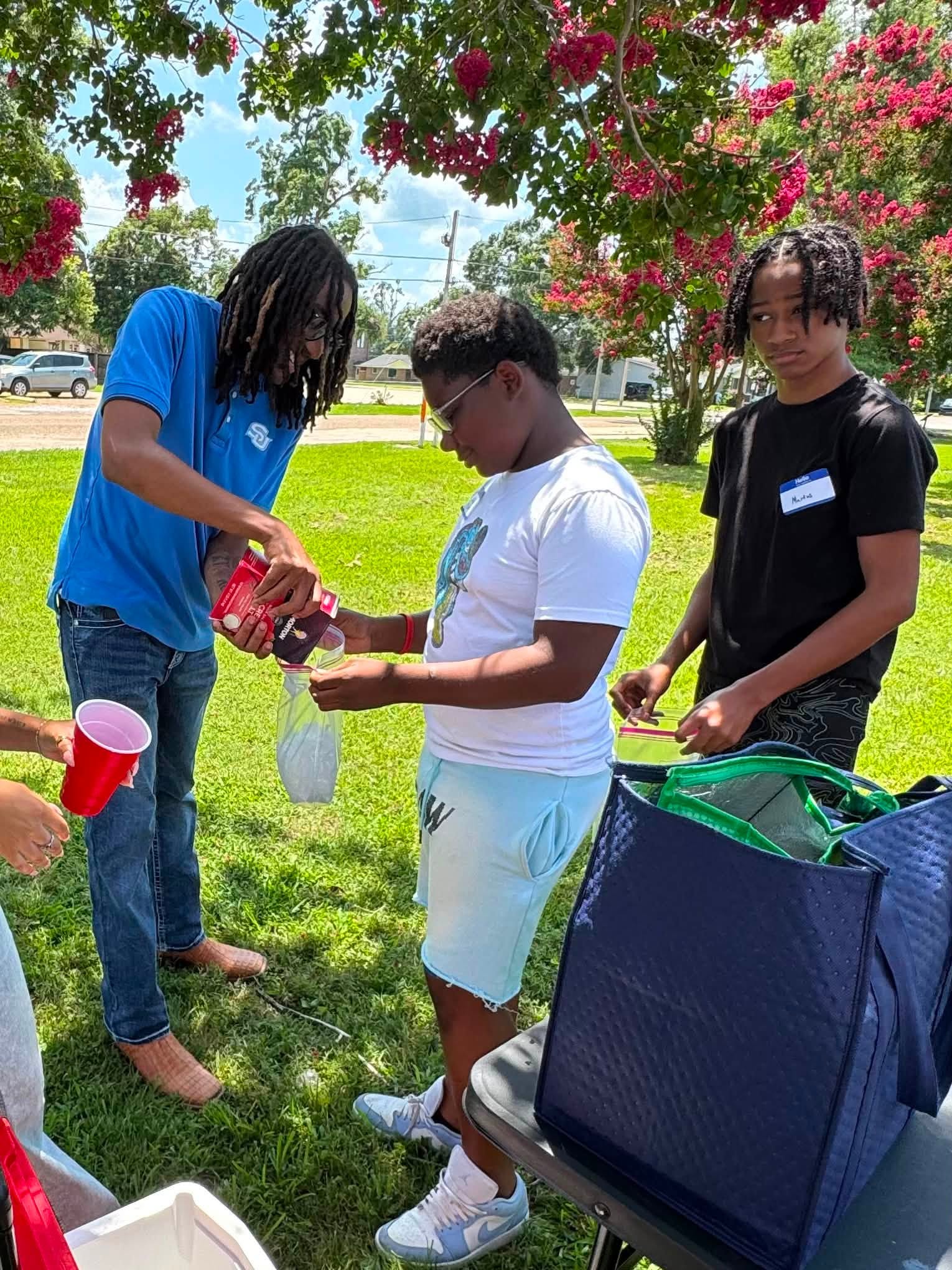 A boy holding a clear bag while a man pours something into it.